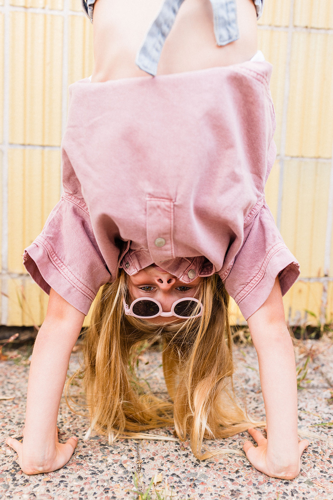 Mädchen trägt rosa Flitzkids Kindersonnenbrille und macht einen Handstand