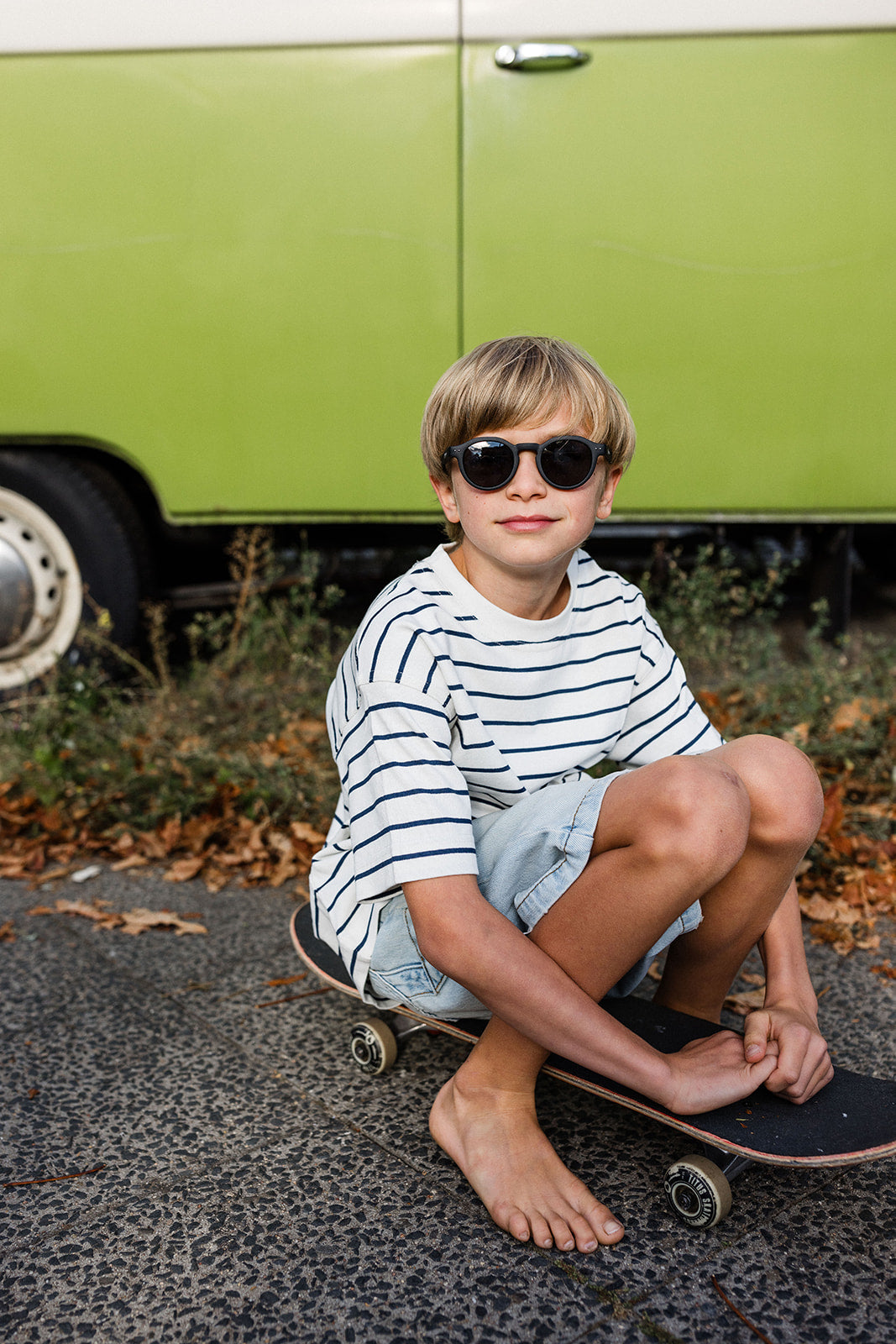Junge mit Skateboard trägt schwarze Kindersonnenbrille